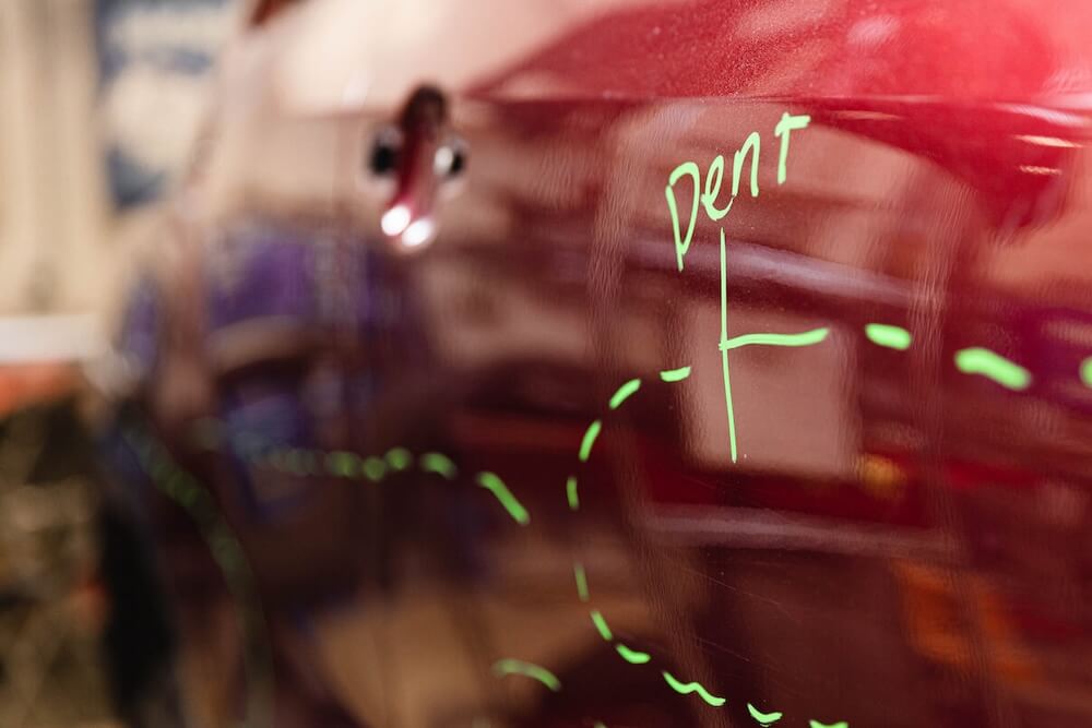 A dent outlined by a bright marker on a red car